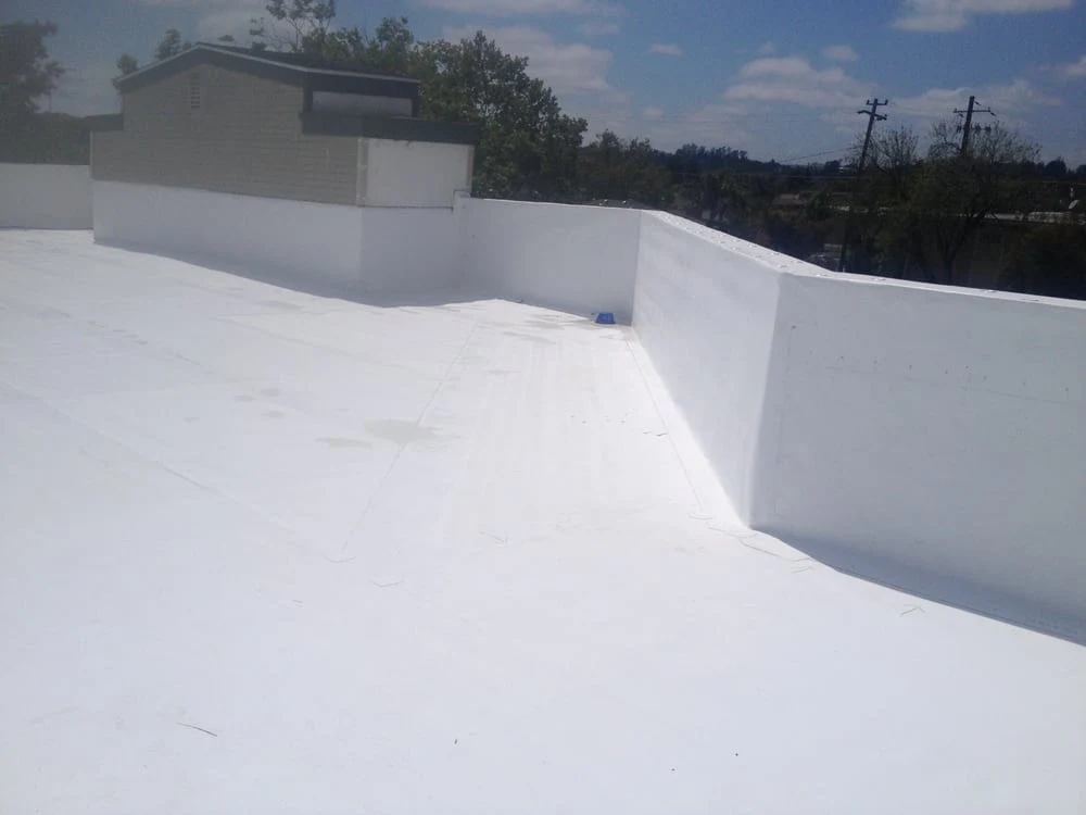 Broad light-colored low-slope roofing surface with perimeter walls