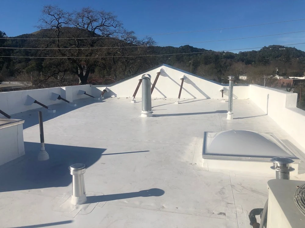 White low-slope roof with raised perimeter walls and roof penetrations