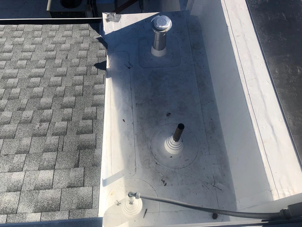 Roof-edge junction between gray shingles and a light-colored low-slope roof section