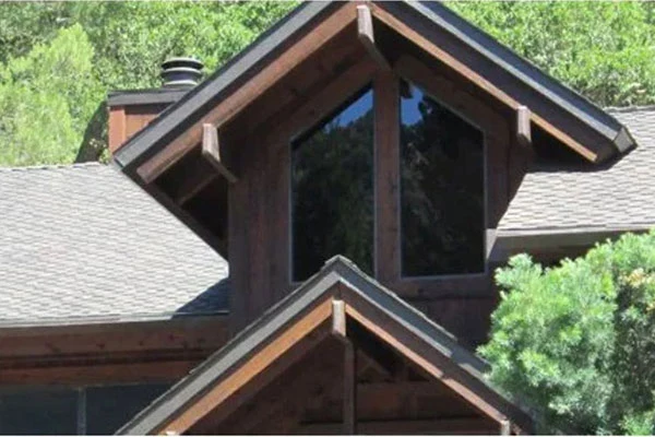 Shingle roof meeting a tall wood-sided roof structure